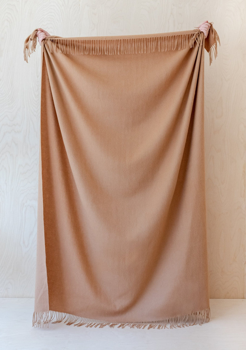 TBCo Lambswool Blanket in Camel with fringed edges displayed vertically against white backdrop